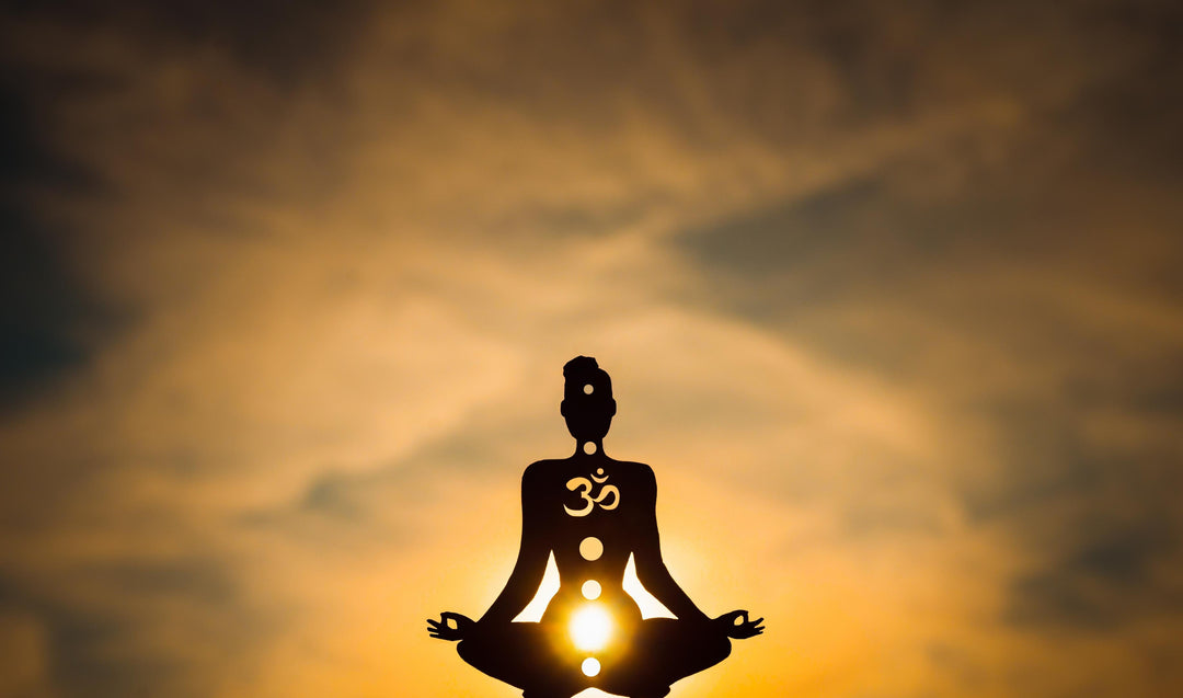 Meditating figure with glowing solar plexus chakra energy center and aligned chakra system during sunset