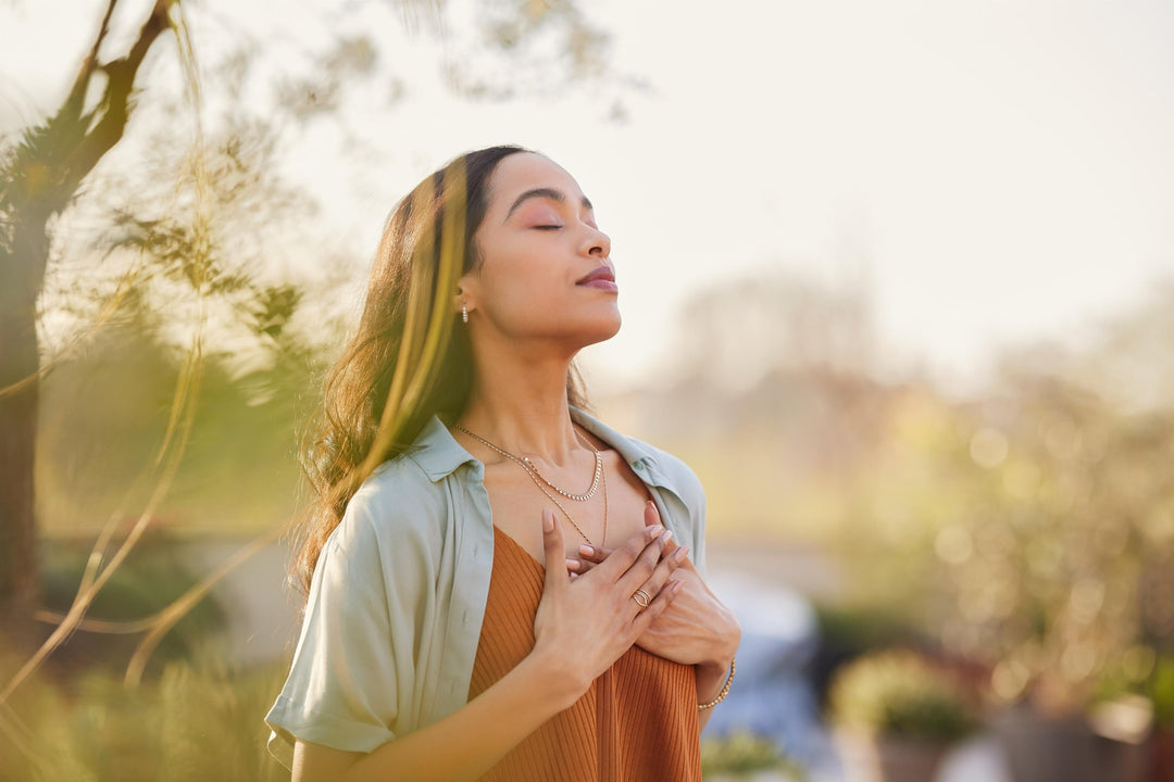 Woman standing in warm sunlight with hands on heart symbolizing the spring equinox and northern hemisphere vernal equinox, representing balance between the northern and southern hemispheres