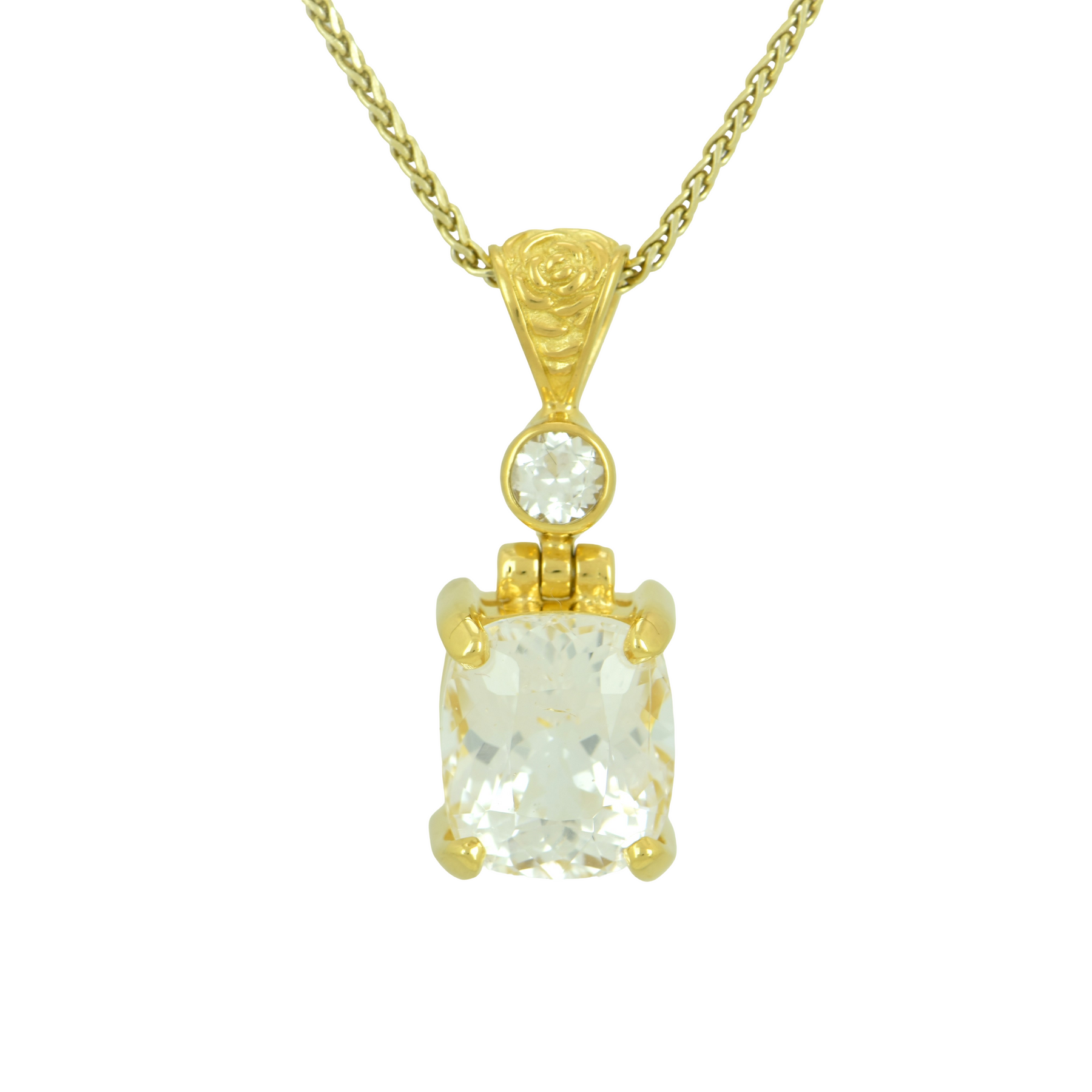 Cushion cut phenakite pendant with a small round white accent stone set in gold with a floral engraved bail on a gold wheat chain